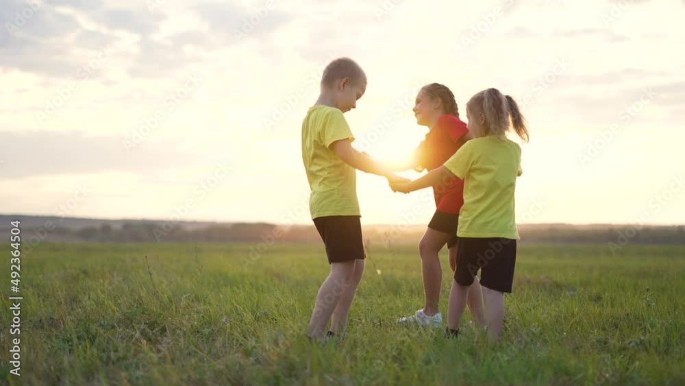 Happy family concept.Group of children holding hand in round dance.Brother and sister are play in park on grass.Active lifestyle concept. Family on green grass. Happy children play round dance in park Happy family concept.Group of children holding hand in round dance.Brother and sister are play in park on grass.Active lifestyle concept. Family on green grass. Happy children play round dance in park