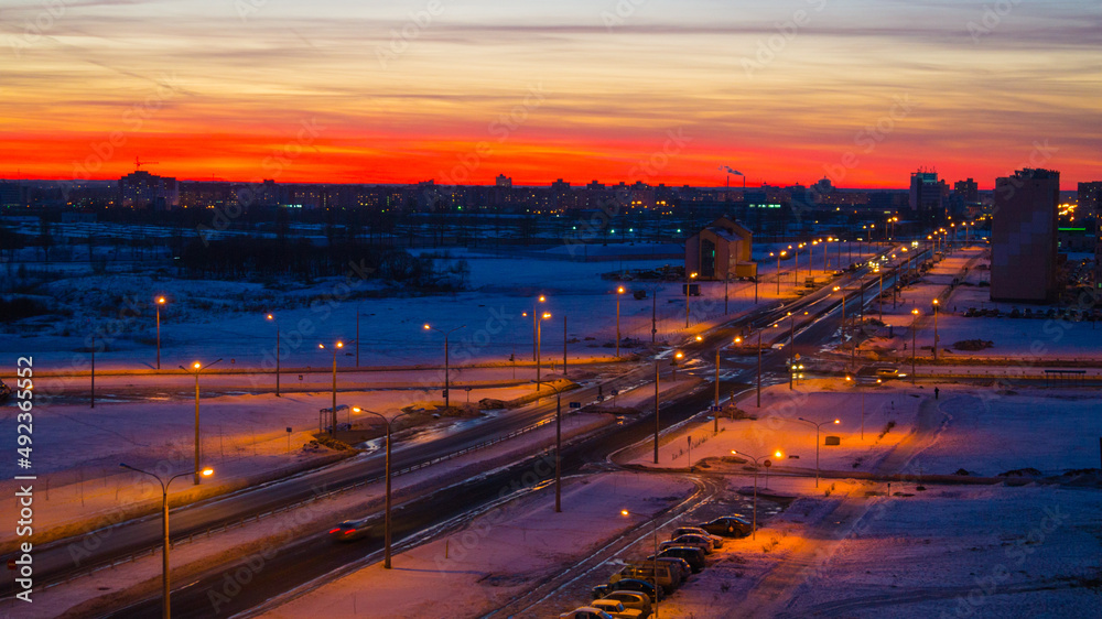 Winter sunset over the city street, houses, snow-covered road, wide angle