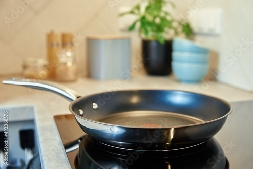 Fototapeta Steel frying pan in the kitchen on electric induction hob, Modern kitchen applia