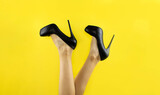 Woman in black shoes on a yellow background. Black shoes from the new collection on a yellow background. Legs of a woman in shoes. background. yellow background