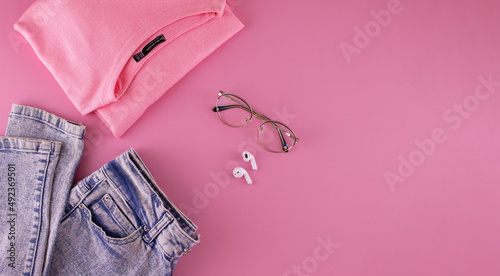 Women's clothing and accessories on a pink background, top view. Modern and casual outfit. Fashion, shopping and makeup concept.