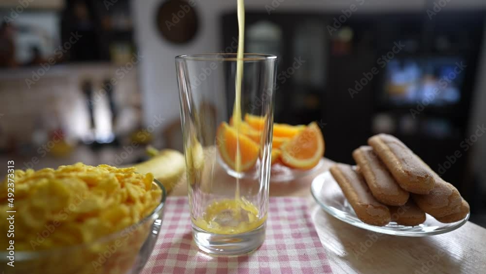Pouring fresh orange juice into a transparent glass on a rotating table in the kitchen, close up, slow motion. Cooking a healthy breakfast with natural organic vitamin drink Pouring fresh orange juice into a transparent glass on a rotating table in the kitchen, close up, slow motion. Cooking a healthy breakfast with natural organic vitamin drink
