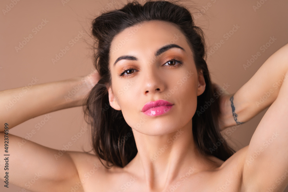 Young woman with wavy voluminous hair on a beige background with bright pink lipstick lip gloss topless bare shoulders Young woman with wavy voluminous hair on a beige background with bright pink lipstick lip gloss topless bare shoulders