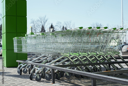 Side view of many parked new, empty shopping carts in an outdoor supermarket parking lot