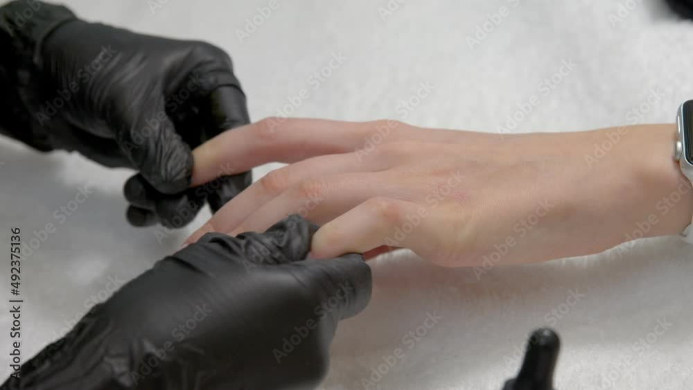 A close-up of a master doing a manicure to a young girl in a beauty salon. The concept of nails, manicure, beauty, fashion. A close-up of a master doing a manicure to a young girl in a beauty salon. The concept of nails, manicure, beauty, fashion.