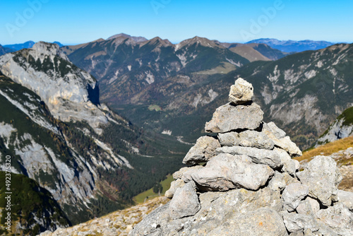 Mountain view with a stacked rock pile, during a hiking trail on a sunny day. (selective focus)