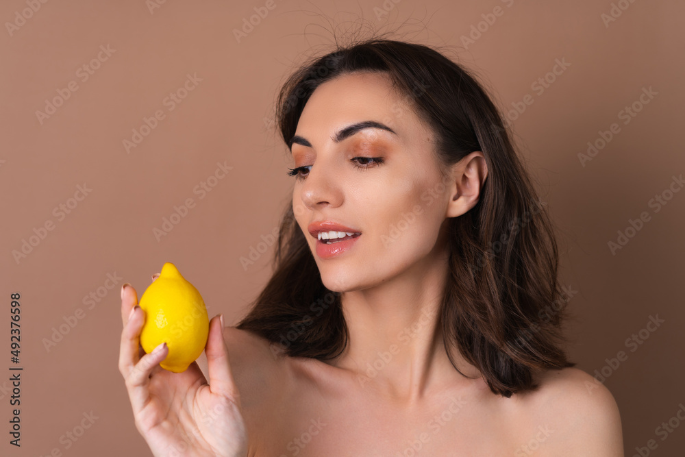 Beauty portrait of topless woman with perfect skin and natural make-up on a beige background holds citrus lemon, vitamins c for skin Beauty portrait of topless woman with perfect skin and natural make-up on a beige background holds citrus lemon, vitamins c for skin