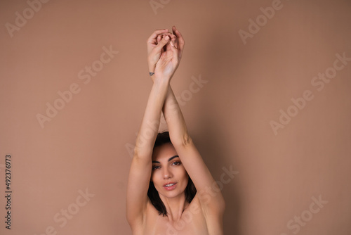 Beauty portrait of topless woman with perfect skin and natural make-up on beige with smooth armpits without hair laser hair removal