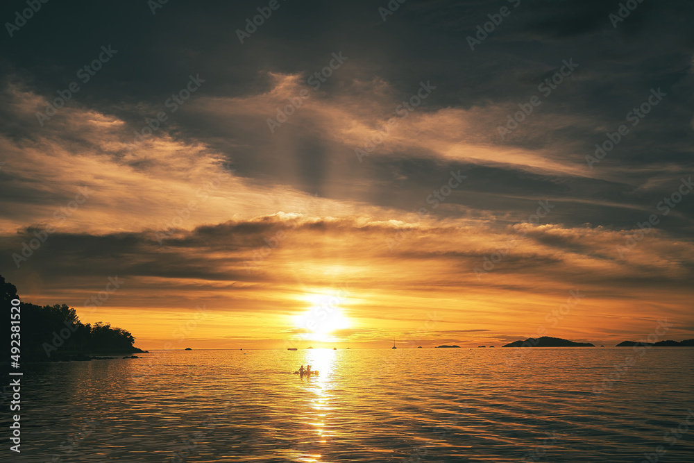 Dramatic sunset over sea with clouds in the sky and canoe rider in the foreground - Thailand Koh Lipe