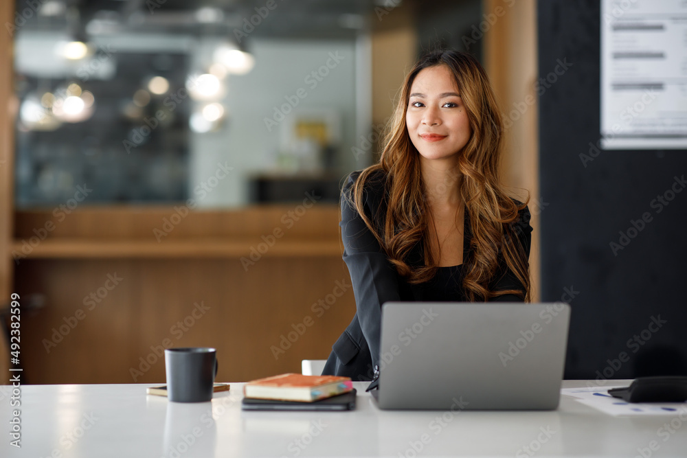 Charming Asian businesswoman sitting in the office with a digital laptop computer. Excited Asian businesswoman raising hands to congratulate while working in a modern office, Charming Asian businesswoman sitting in the office with a digital laptop computer. Excited Asian businesswoman raising hands to congratulate while working in a modern office,