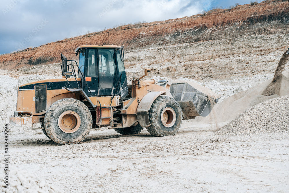 Wheel loader with large bucket on construction site or quarry. Mining heavy machinery details. Earthmoving, excavations, digging on soils. Wheel loader with large bucket on construction site or quarry. Mining heavy machinery details. Earthmoving, excavations, digging on soils.