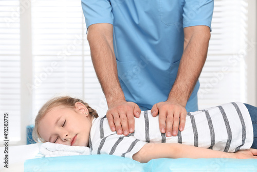 Orthopedist massaging child's back in clinic, closeup. Scoliosis treatment