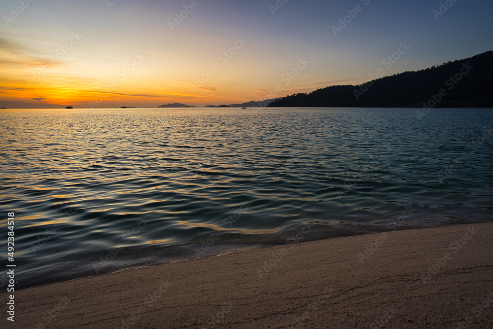 Obraz premium Sand beach with mountains and clouds during a sunset over the sea in the background - Thailand Koh Lipe