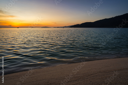 Sand beach with mountains and clouds during a sunset over the sea in the background - Thailand Koh Lipe