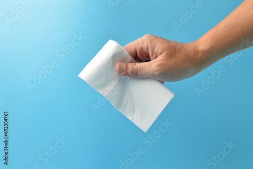 Tela Hand holding white paper tissue isolated on a blue background