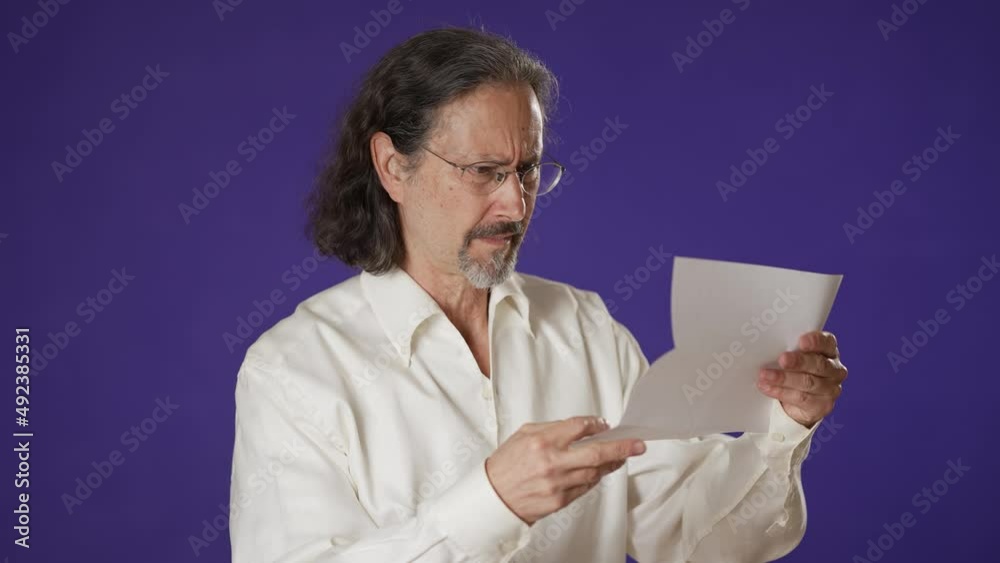 Portrait of angry stressed man reading bad news in mail letter. Mad man feels frustrated about high bills, dismissal notice, bank debt, tax invoice or mistake on solid purple background. Portrait of angry stressed man reading bad news in mail letter. Mad man feels frustrated about high bills, dismissal notice, bank debt, tax invoice or mistake on solid purple background.