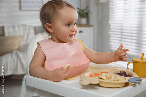 Cute little baby wearing bib while eating at home