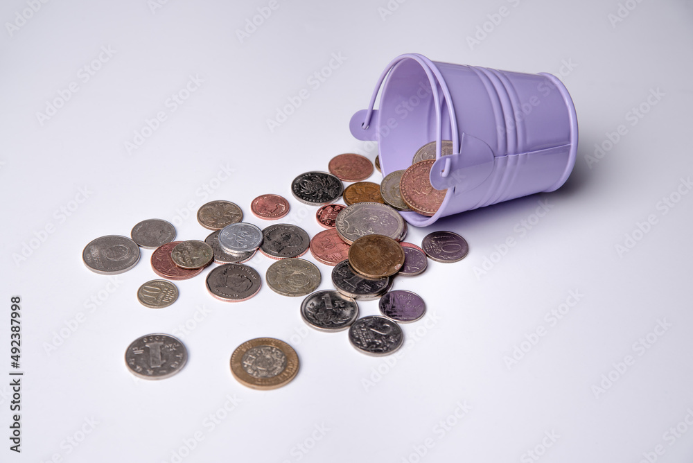 Scattered money coins in a bucket. The received multicurrency income