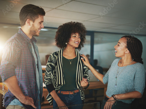 Friendly office banter keeps things fresh and fun. Shot of colleagues talking in a modern office.
