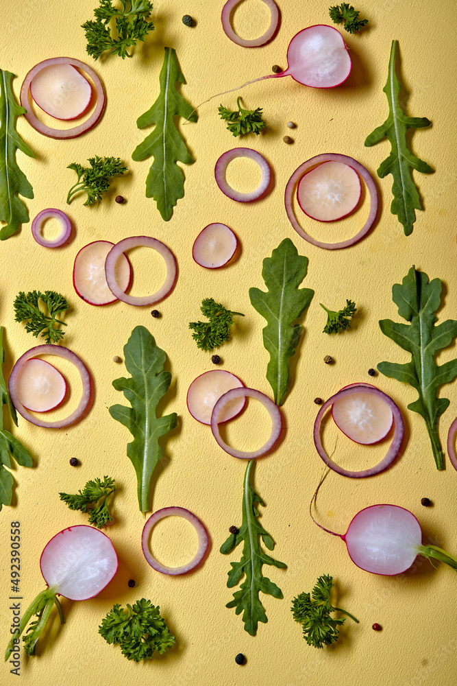 Top view on onion slices, radish and fresh herbs isolated on yellow wall background. above view. flat lay, copy space. vegetables with vitamins for healthy lifestyle Top view on onion slices, radish and fresh herbs isolated on yellow wall background. above view. flat lay, copy space. vegetables with vitamins for healthy lifestyle