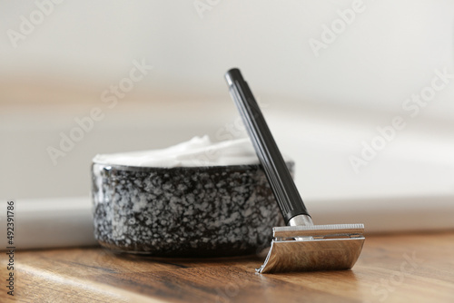 Shaving razor and foam on table in bathroom