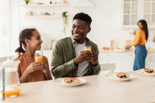 Happy African Father And Daughter Drinking Orange Juice In Kitchen