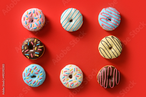 Frame made of different sweet donuts on red background