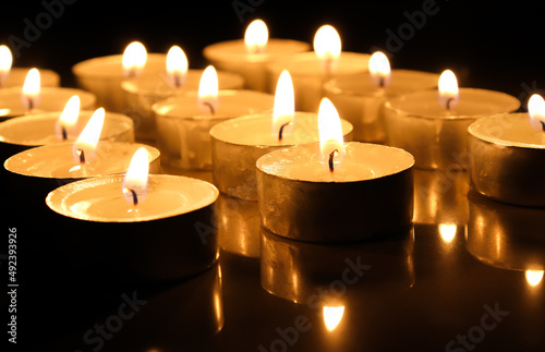 pointLots of candles on a wooden in the darkness tablefocusspot specifically in on a dark color background.