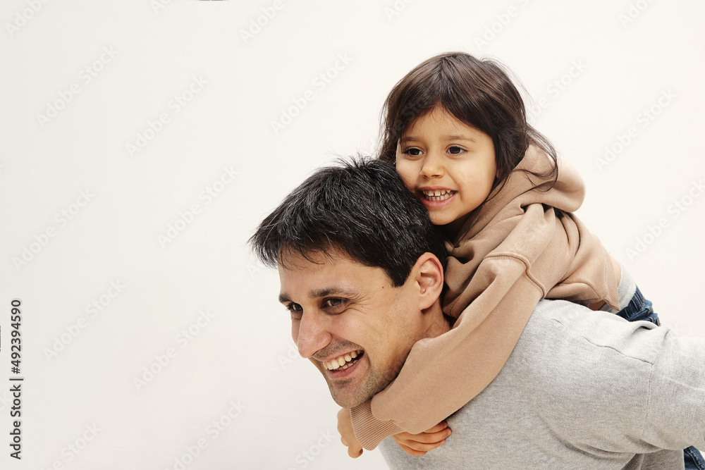 Portrait of excited little girl sitting on her back, young father playing together at home, happy loving dad feeling playful, continuing happy little daughter, family weekend concept Portrait of excited little girl sitting on her back, young father playing together at home, happy loving dad feeling playful, continuing happy little daughter, family weekend concept