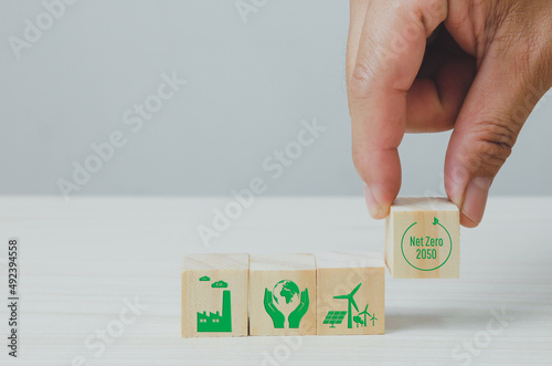 Wooden cubes with net zero and carbon neutral green factory icon symbol background and copy space.