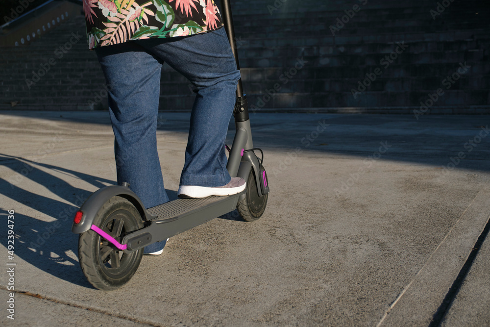 Obraz premium Unrecognizable woman with her electric kick scooter in the city, eco transport