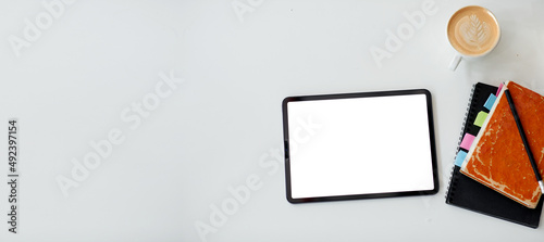 Digital tablet screen on a wooden background, note coffee cup business desk with blank white screen,