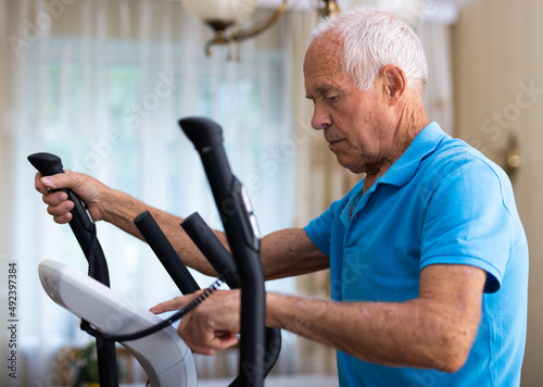 Male is working out on elliptical machine for elder healthy concept