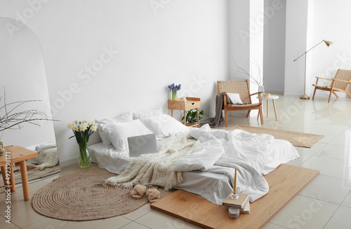 Interior of light bedroom with flowers in vases