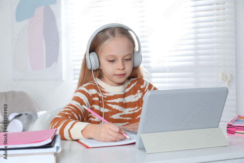 Cute little girl with modern tablet studying online at home. E-learning Cute little girl with modern tablet studying online at home. E-learning