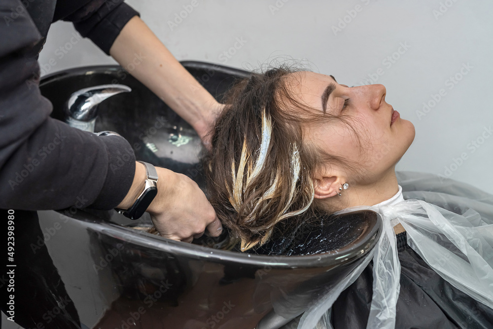 Fototapeta premium in an elite hairdresser's beautiful young woman washes her head in a special chair.