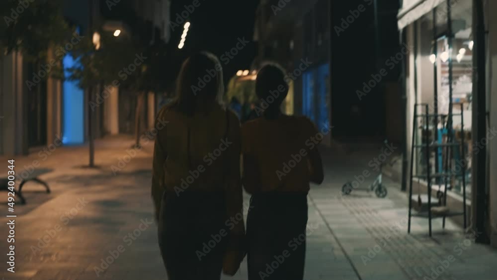 Mom and daughter walk through the night city in summer. Mom and daughter walk through the night city in summer.