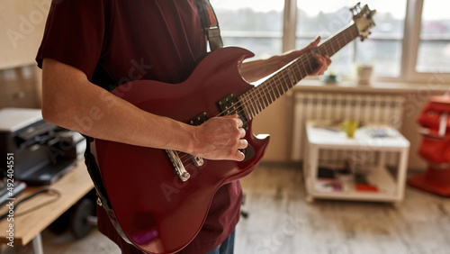 Partial of musician play electric guitar at home
