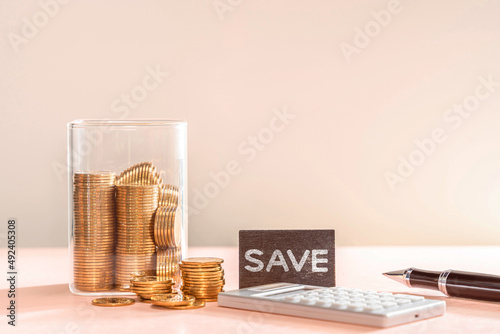 Many gold coins were put in a savings box, a calculator and a pen were placed together. Financial planning for future expenses or for emergencies concept.