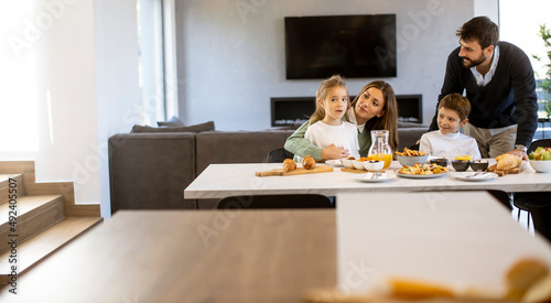 Young happy family talking while having breakfast at dining table