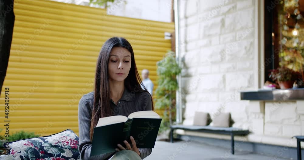 Smiling young woman is reading interesting book outdoor, leafing through a book, Summer chill, Relaxing lifestyle woman concept. Cute student reading book concentrated. Cute Woman Relaxing. Smiling young woman is reading interesting book outdoor, leafing through a book, Summer chill, Relaxing lifestyle woman concept. Cute student reading book concentrated. Cute Woman Relaxing.