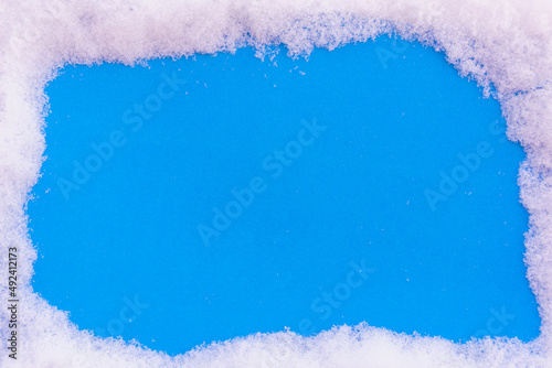 Blue background sprinkled with snow with space for text.