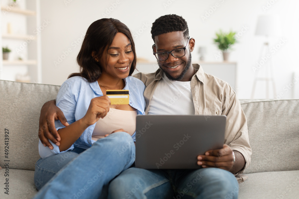 Black couple using pc and debit credit card at home Black couple using pc and debit credit card at home