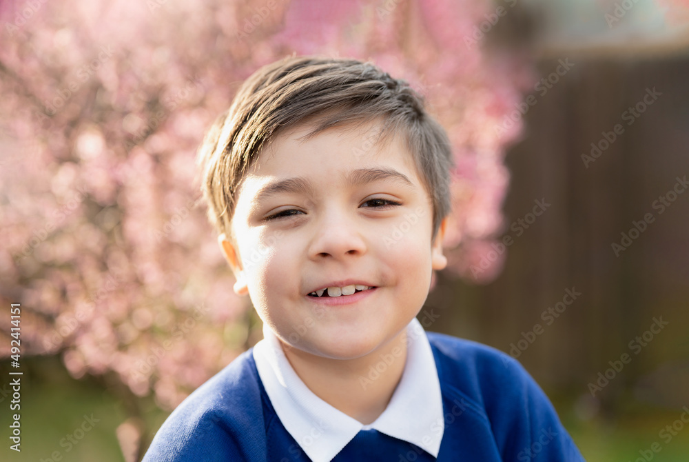 Portrait happy young boy looking at camera with smiling face, School kid standing in the front garden waiting for school bus in the morning Portrait happy young boy looking at camera with smiling face, School kid standing in the front garden waiting for school bus in the morning