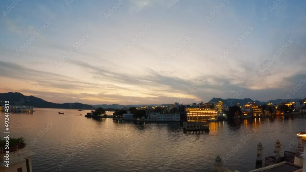4k timelapse of Udaipur city during sunset with dramatic cloudy sky. Lake Pichola with palace and buildings on shore. Moon rising at dusk over a city, day to night time lapse. 4k timelapse of Udaipur city during sunset with dramatic cloudy sky. Lake Pichola with palace and buildings on shore. Moon rising at dusk over a city, day to night time lapse.