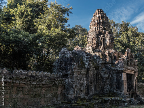 Ancient stone wall and entrance tower with sacred faces in Angkor complex, Siem Reap, Cambodia