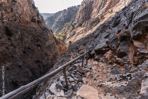 Path along narrow mountain gorge with sheer stone walls and rare bushes, Aradena Gorge, Crete Greece photo