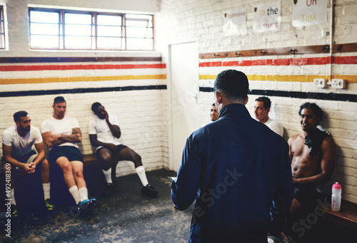 So heres what were going to do.... Cropped shot of a rugby coach addressing his team players in a locker room during the day. photo