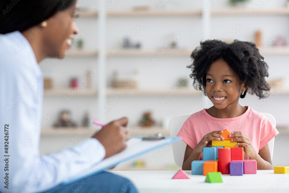 Child development specialist having session with cheerful little girl