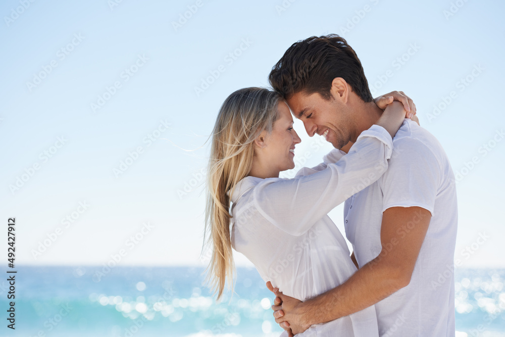 Sharing a moment in the sunshine. A young, affectionate couple at the beach. Sharing a moment in the sunshine. A young, affectionate couple at the beach.
